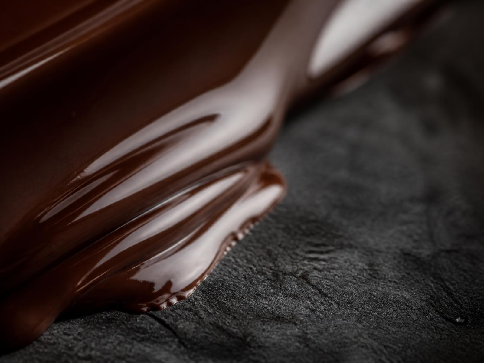 Tempered dark chocolate flowing across a stone surface